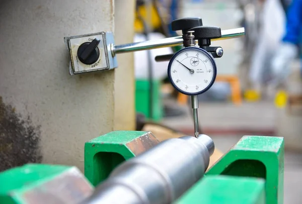 Technician measuring shaft run-out by Dial Gauge. Metal shaft put on the green support.