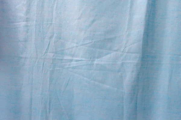 Light blue creased fabric close-up, top view background.