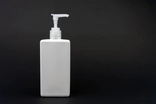 Siyah zemin üzerinde antiseptik olan beyaz plastik şişe..