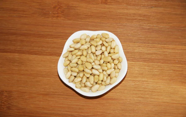Tahta Üzerinde Beyaz Bir Tabakta Çam Fıstığı Kahverengi Bej Beyaz — Stok fotoğraf