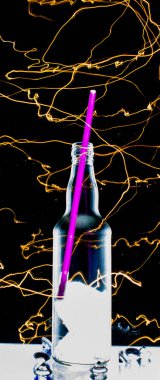 Ön planda cam şişe. Hafif boyayla çerçevelenmiş.