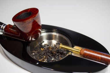 fresh tobacco in ashtray with pipe stopper and pipe