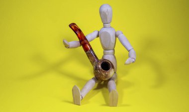 Oturan tahta bebek kollarında güzel bir pipo tutuyor.