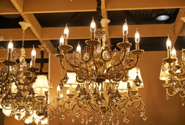 Many gilt beautiful chandeliers hanging from the ceiling in the sales area. — Stock Photo, Image