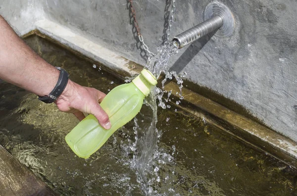 Ręka napełniania wody w butelce z tworzywa sztucznego — Zdjęcie stockowe