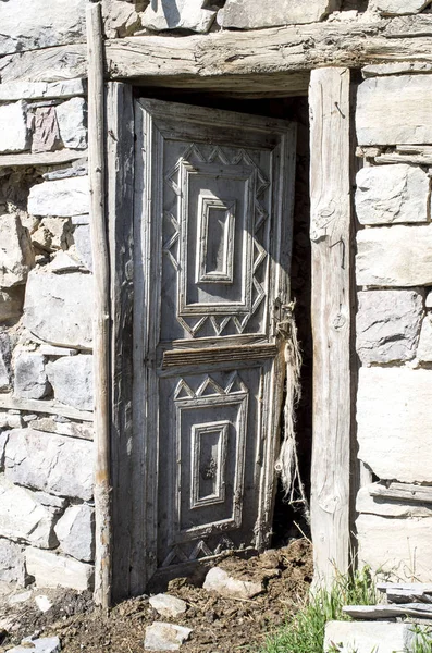 Porta di legno aperta con ornamenti sulla stalla nella vecchia casa di pietra — Foto Stock