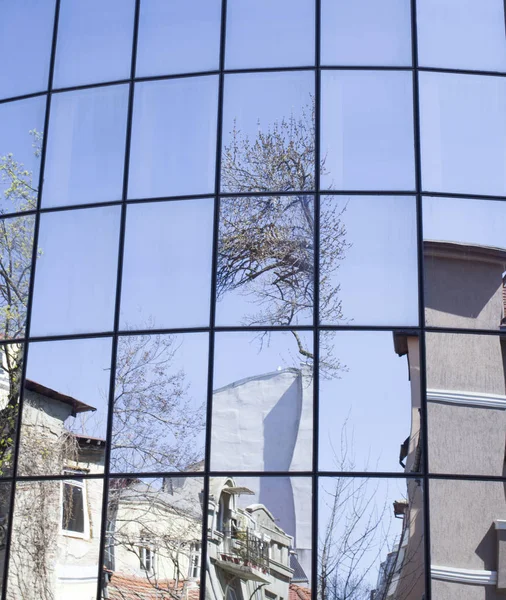 Reflexões de casas e árvores em um novo edifício de vidro — Fotografia de Stock