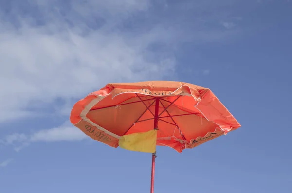 An orange umbrella with a yellow flag of lifeguard — Stock Photo, Image