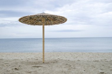 Bulutlu gün sahilde yalnız baston şemsiye