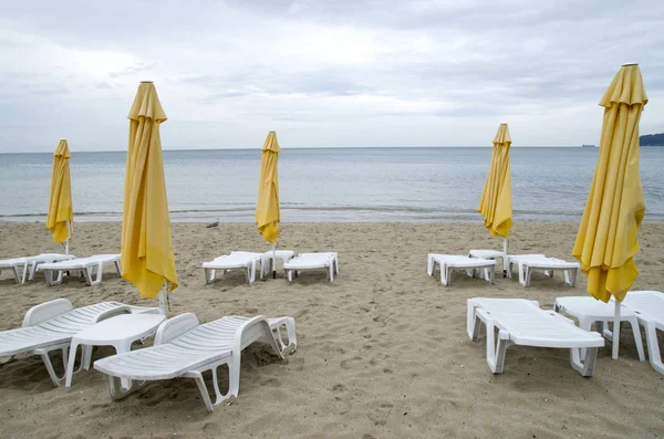 Sombrillas y tumbonas de plástico en la playa en día nublado —  Fotos de Stock