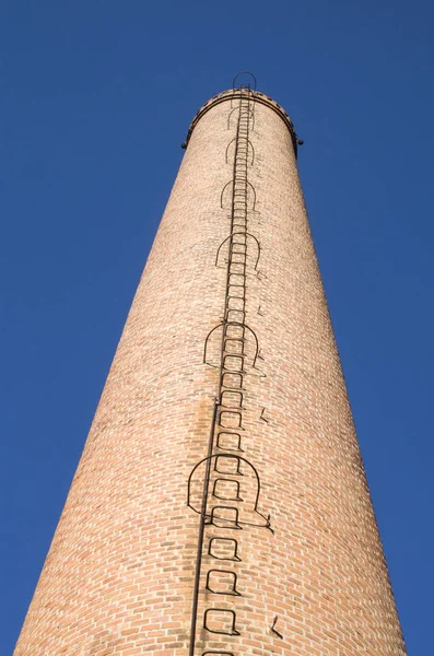 Труба из кирпича с металлической лестницей — стоковое фото