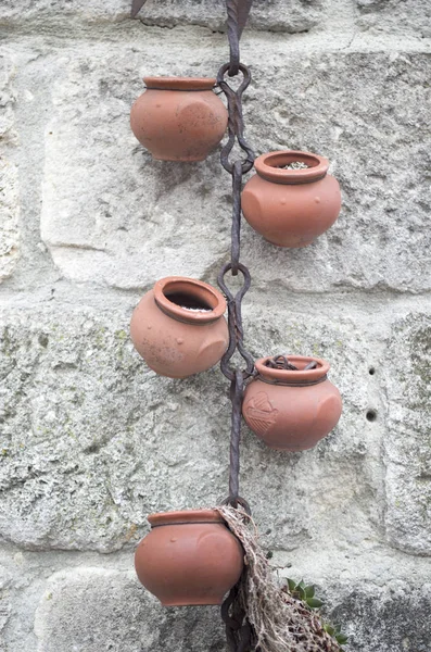 Element dekoracyjny garnki i zardzewiały łańcuch na ścianie — Zdjęcie stockowe
