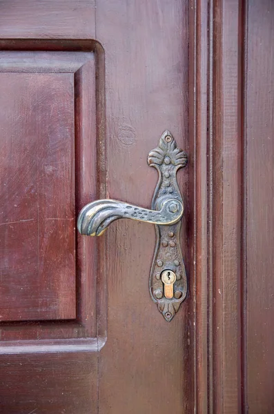 Old handle on wooden closed brown door — Stock Photo, Image