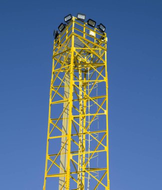 Yellow metal tower with many led lamps in sky