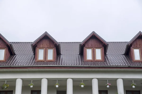 Several wooden dormers with windows on new brown metal roof