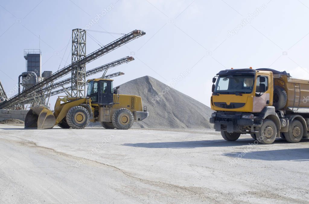 Wheel medium-sized Loader and several belt conveyors and piles of rubble in Gravel Quarr