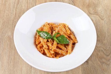 Fesleğen yapraklı karides makarna ve ahşap zemin üzerinde beyaz bir tabakta parmesan peyniri.