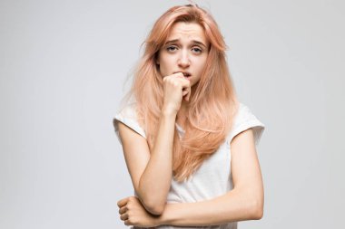 Cropped studio portrait of cute blonde girl in white t-shirt looks with bewilderment and disappointment/closed posture, angry, strict and skeptical expression, negative emotion, destruct.