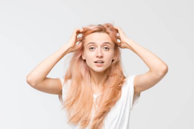Beyaz tişörtlü güzel sarışın kızın stüdyo portresini kapat. Kadın saçına elini kaldırdı ve kameraya baktı. Sürpriz bir ünlem. Şaşırmış bir kadın. Duygular konsepti.