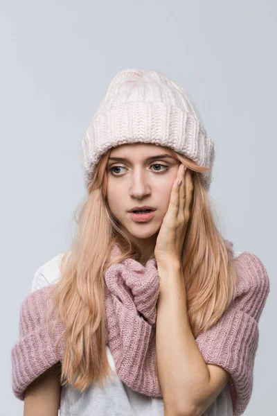 Pembe kazaklı ve beyaz şapkalı bir kadının kapalı bir fotoğrafı hatasını anlıyor, üzgün bir ifadeyle / yanlış bir kararla, düşünceli bir ifadeyle, şaşkın bir kadınla, olumsuz duygularla bakıyor..