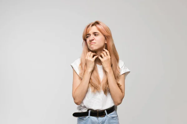 Beyaz tişörtlü, boynu kaşınan, tahriş olan, hassas cilt, alerji belirtileri, burun iltihabı, soğuk, kaşıntı, sağlık ve tıp konsepti olan güzel bir kadının izole edilmiş stüdyo portresi..