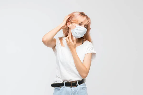 喉を掻く医療マスクで白いTシャツの悲しい若い女の子のスタジオの肖像画 乾燥肌 敏感肌 アレルギー症状 皮膚炎 虫刺され 医療の概念 — ストック写真