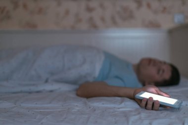 Adam yorgunluk sonucu elinde akıllı telefon ile uyuyakaldı. Erkek telefonu çok kullanır ve uyku bozukluklarından muzdariptir. Birikmiş yorgunluk, yeterli uyku yok. Telefona seçici odaklanma