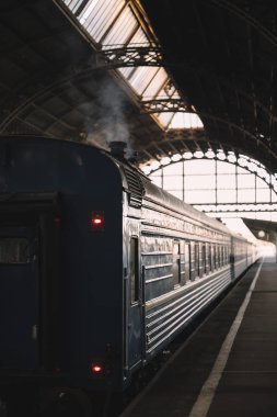 Retro yolcu vagonu kapalı platformdan kalkmaya hazırlanıyor. Duman bacadan kaçar. Antika tren vagonunun dışı. Dikey fotoğraf. Tatil ve turizm konsepti.
