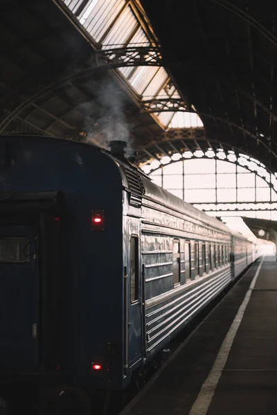 Retro yolcu vagonu kapalı platformdan kalkmaya hazırlanıyor. Duman bacadan kaçar. Antika tren vagonunun dışı. Dikey fotoğraf. Tatil ve turizm konsepti.