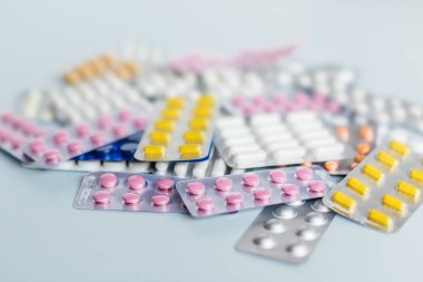 Çeşitli ilaçlar: beyaz, pembe ve sarı ilaç hapları, grip ilacı, baş ağrısı hapları, antibiyotikler. Tıbbi ve sağlık hizmetleri konsepti. Kesilmiş fotoğraf, yumuşak odak.