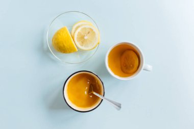 Soğuk algınlığı için ev yapımı ilaçlar: bir fincan çay, bir fincan limon ve bal. Doğal yollarla tedavi. Tıbbi ve sağlık hizmetleri konsepti. Düz yatış, üst görünüm.