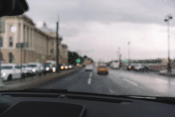 近照雨滴落在挡风玻璃上 有选择性的焦点 模糊的车的背景 薄薄的玻璃丝加热 多雨的季节汽车工业 空荡荡的路车内的舒适 — 图库照片
