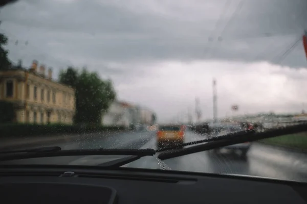 挡风玻璃上的雨滴的近照 选择性的聚焦 模糊的车辆在交通堵塞的背景下 薄薄的玻璃丝加热 多雨的季节汽车工业 雨刷把挡风玻璃擦干净 — 图库照片