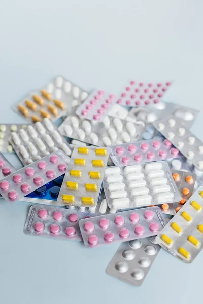 Çeşitli ilaçlar: beyaz, pembe ve sarı ilaç hapları, grip ilacı, baş ağrısı hapları, antibiyotikler. Tıbbi ve sağlık hizmetleri konsepti. Kesilmiş dikey fotoğraf, yumuşak odak.