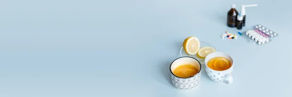 家庭内治療と薬 民間療法を扱う 前景では レモンと蜂蜜のソーサーのカップ 背景には さまざまな薬 インフルエンザや鼻水の救済策 スペースのコピー — ストック写真