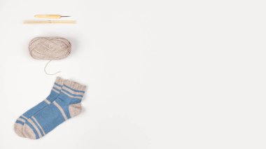 Tahta örgü iğneleri, bambu kancası bej iplik topu ve yün mavi-gri çoraplar. Uzayı kopyala Tığ işi. Düz yatıyordu. İğne işi ve eğlence konsepti. Kadın hobisi. Tasarımınız için şablon.