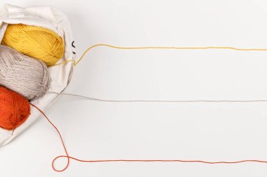 Tekstil çantasındaki sarı, kırmızı ve bej renkli iplikler. İplik dizileri metin için bir satır oluşturur. Uzayı kopyala, kapat. İğne işi ve eğlence konsepti. Kadın hobisi. Tasarımınız için şablon.