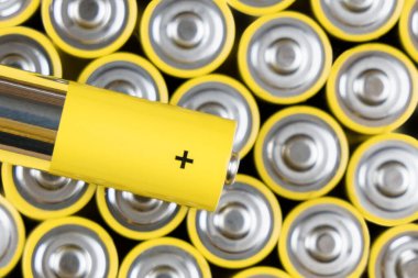 Gri-sarı alkali AA bataryaların pozitif uçlarında üst görünüm. Şarj edilebilir NiMH pillerin geri dönüşümü. Akümülatörlerin en popüler boyutu. Makro fotoğraf, şablon geçmişi. Seçici odak.