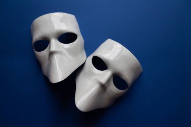 Klasik mavi arka planda beyaz maskeli tiyatro konsepti. Anonimous, Incognito, Conspiracy konsepti. Mesaj için yer. Düz yatış stili. Üst görünüm