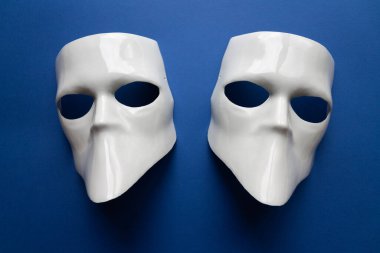 Klasik mavi arka planda beyaz maskeli tiyatro konsepti. Anonimous, Incognito, Conspiracy konsepti. Mesaj için yer. Düz yatış stili. Üst görünüm