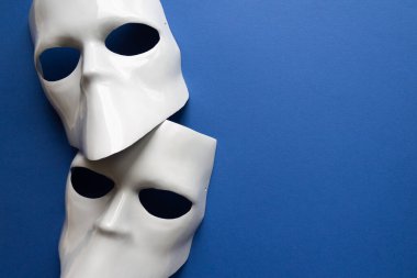 Klasik mavi arka planda beyaz maskeli tiyatro konsepti. Anonimous, Incognito, Conspiracy konsepti. Mesaj için yer. Düz yatış stili. Üst görünüm