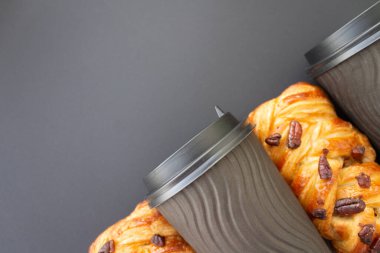 Kahve konsept olsun. Siyah plastik kaplamalı, sarmal desenli, tek kullanımlık siyah bardak ve modaya uygun gri arka planda pekan cevizi. Mesaj için yer. Düz yatış stili. Üst görünüm