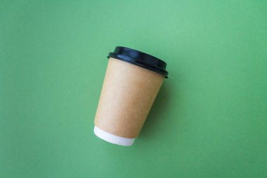 Kahve konsept olsun. Moda yeşili arka planda siyah plastik kaplı tek kullanımlık el bilgisayarı. Mesaj için yer. Düz yatış stili. Üst görünüm