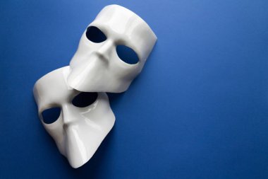 Klasik mavi arka planda beyaz maskeli tiyatro konsepti. Anonimous, Incognito, Conspiracy konsepti. Mesaj için yer. Düz yatış stili. Üst görünüm.