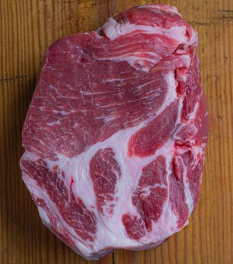 Tahtada çiğ domuz, boynunda biftek.