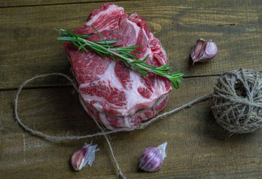 Sarımsaklı çiğ domuz eti ve ahşap arka planda sicimle bağlanmış biberiye.