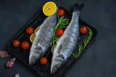 Pişirmeden önce domatesli, biberiyeli ve limonlu taze levrek.