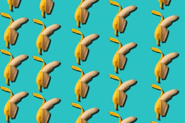 Muzlarla kusursuz bir geçmişi var. Soyut tropikal arka plan. Mavi arka planda yarı soyulmuş muz..