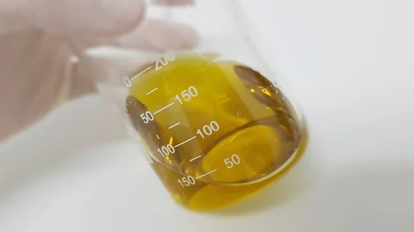 Químico mostrando aceite de oliva en un vaso de precipitados — Foto de Stock