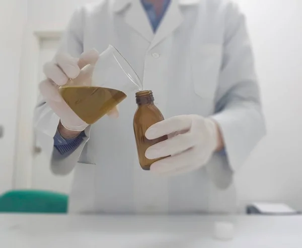 Químico mostrando aceite de oliva en un vaso de precipitados — Foto de Stock